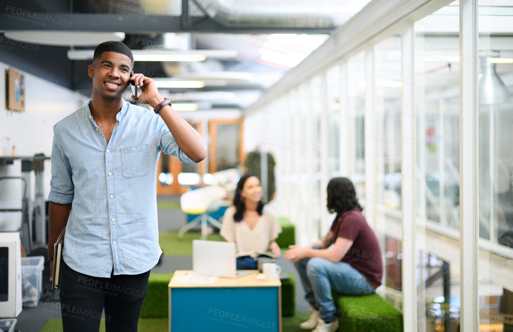 Buy stock photo Shot of a young businessman talking on a cellphone while walking through an office