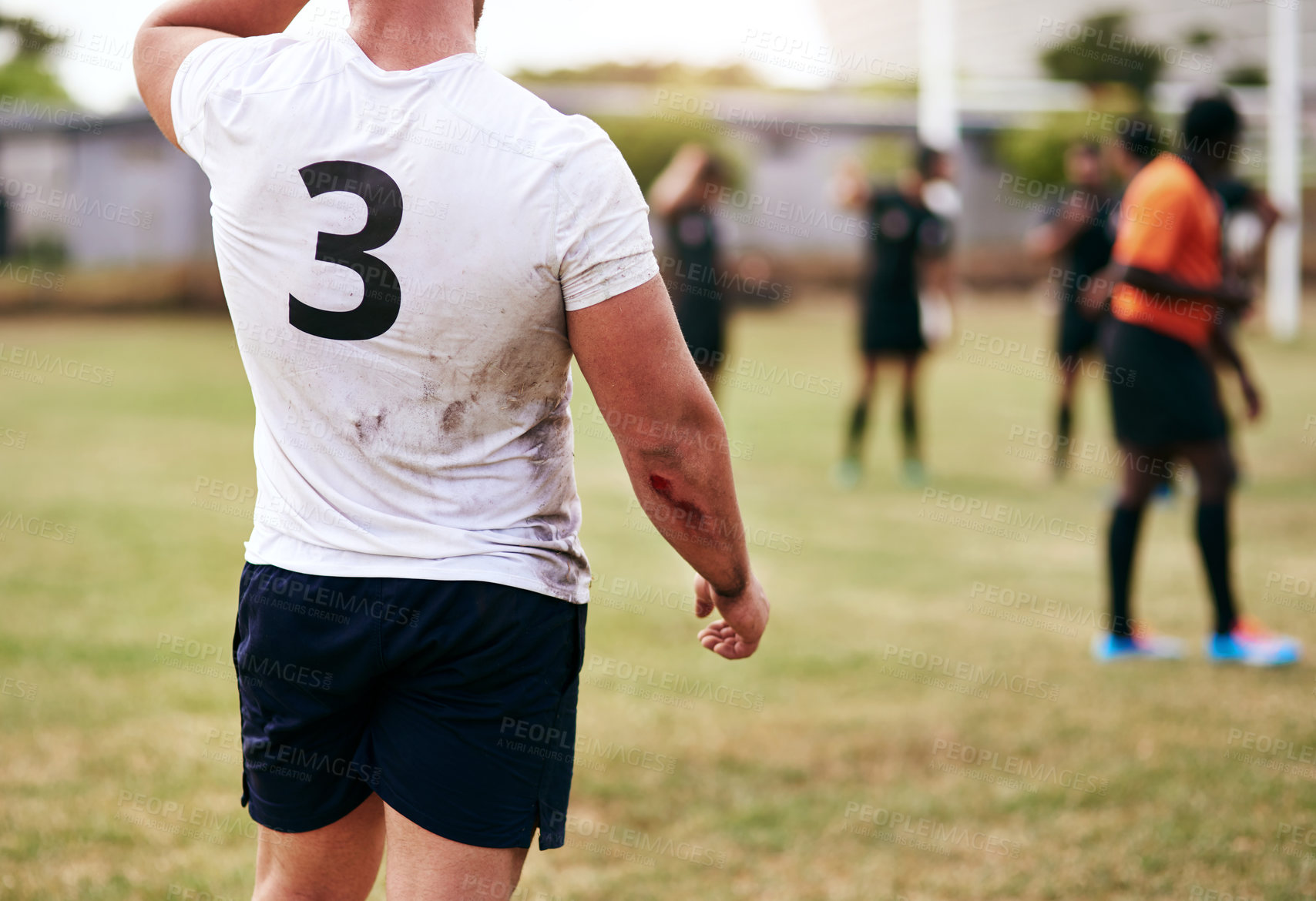 Buy stock photo Cropped shot of a man playing a game of rugby with his teammates in the background