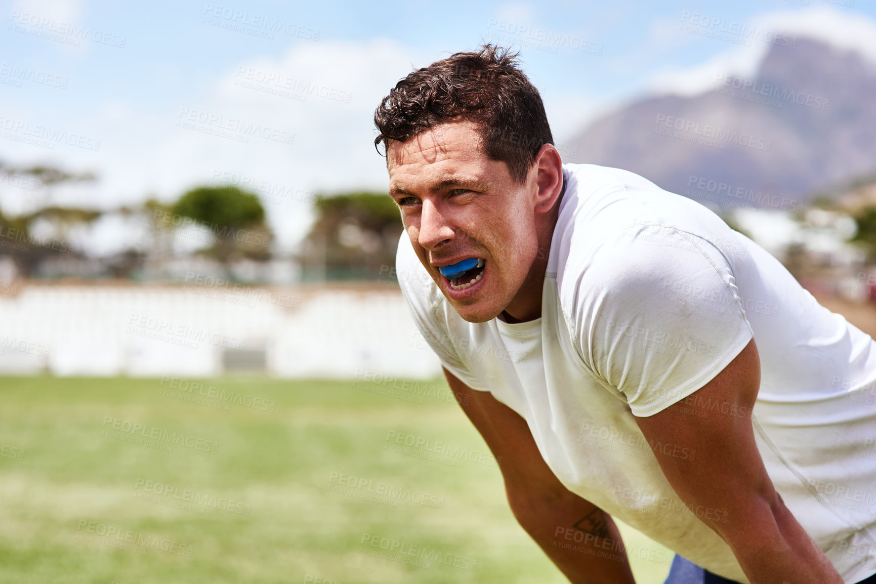 Buy stock photo Shot of a young man wearing a gum guard while playing a game of rugby