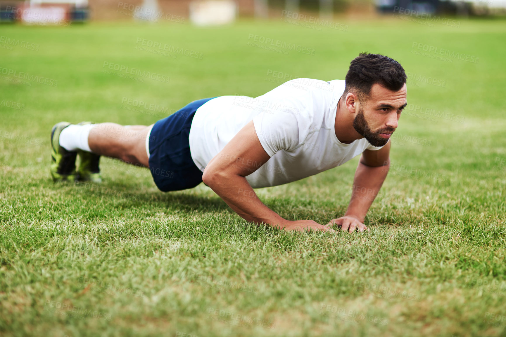 Buy stock photo Shot of a young man doing push ups on a rugby field