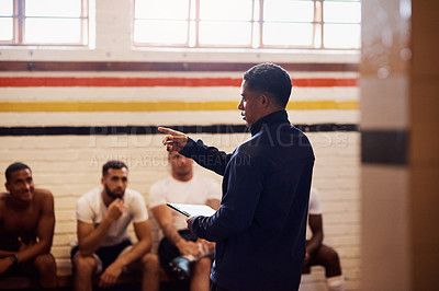 Buy stock photo Shot of a rugby coach addressing his team players in a locker room