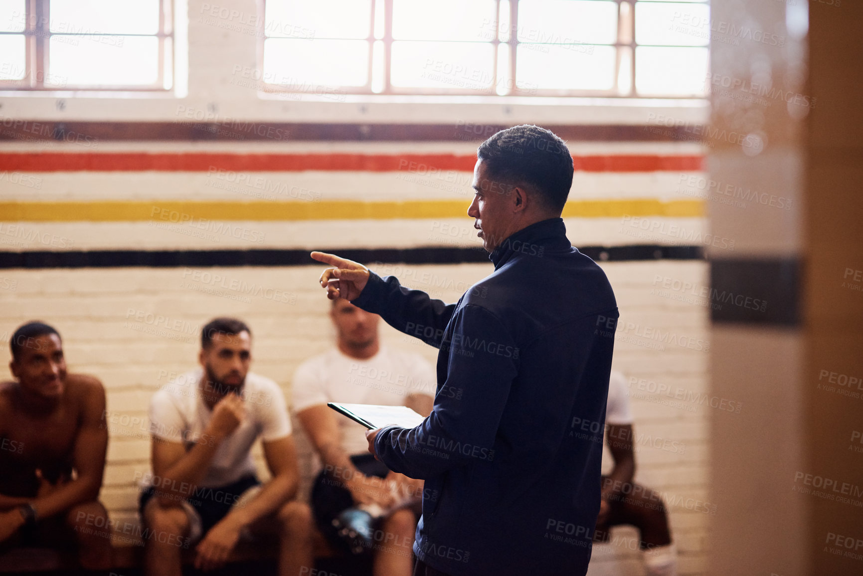 Buy stock photo Shot of a rugby coach addressing his team players in a locker room