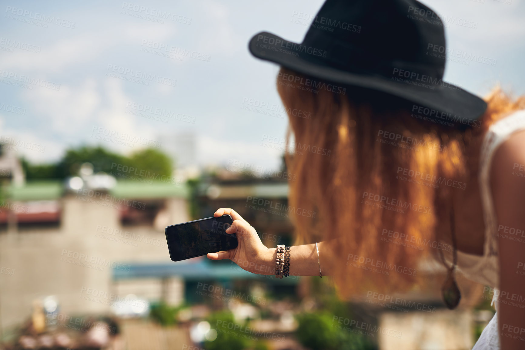 Buy stock photo Cropped shot of a young woman taking pictures on her cellphone while out in the city