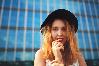 Buy stock photo Shot of a beautiful young woman posing outside against a glass building