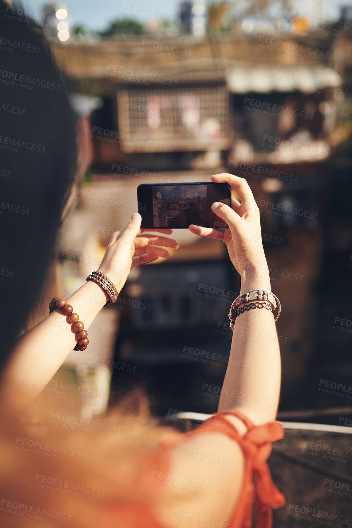 Buy stock photo Cropped shot of a young woman taking pictures on her cellphone while out in the city