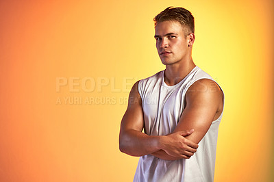 Buy stock photo Studio portrait of a handsome young male athlete standing with his arms folded against an orange background
