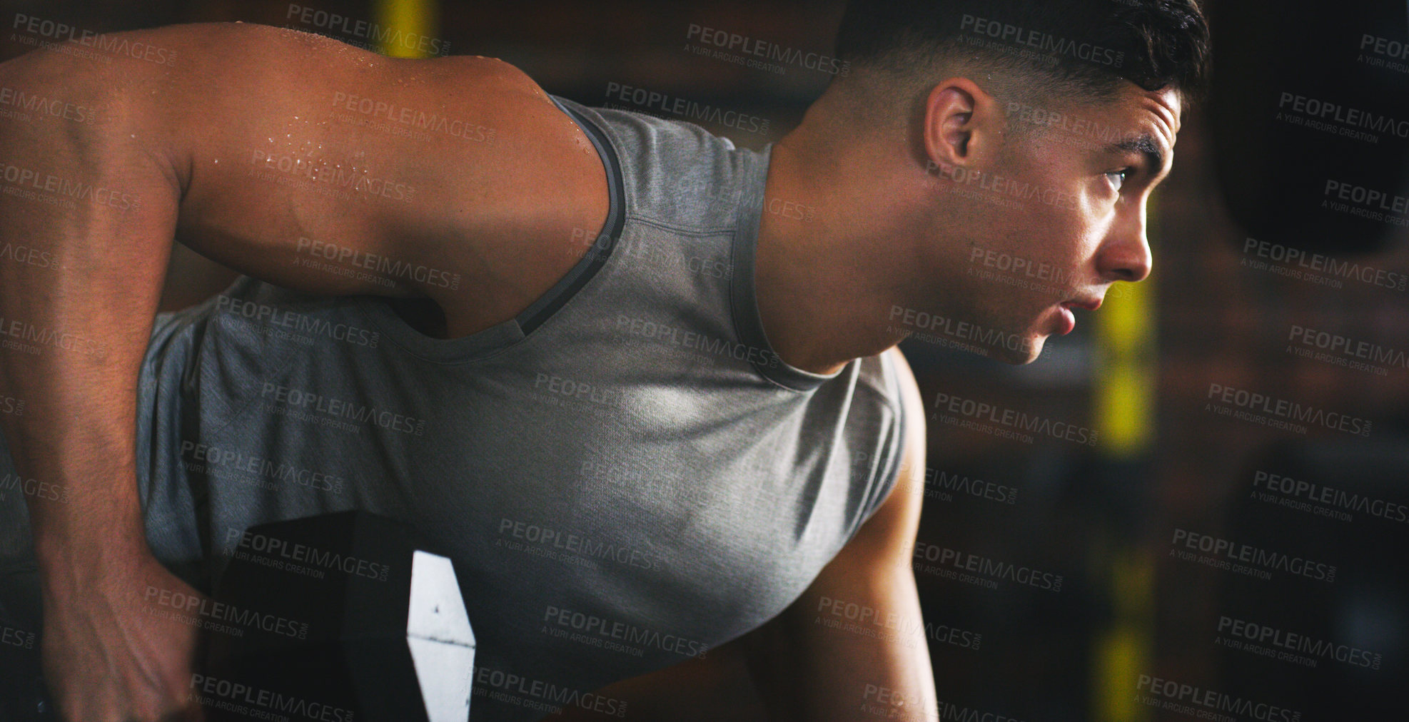 Buy stock photo Shot of a sporty young man exercising with a dumbbell at the gym