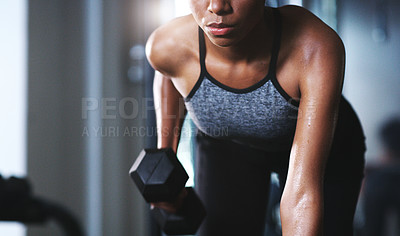 Buy stock photo Shot of a sporty young woman exercising with a dumbbell at the gym