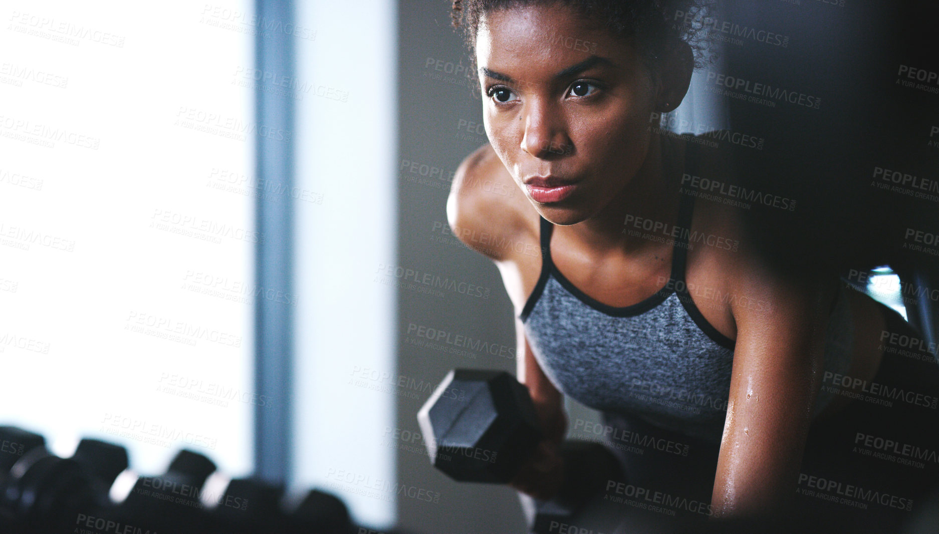 Buy stock photo Shot of a sporty young woman exercising with a dumbbell at the gym