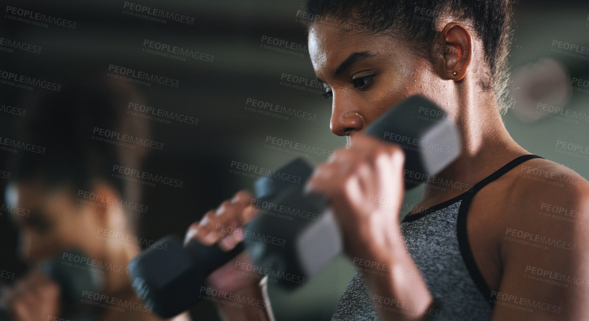 Buy stock photo Shot of a sporty young woman exercising with a dumbbell at the gym