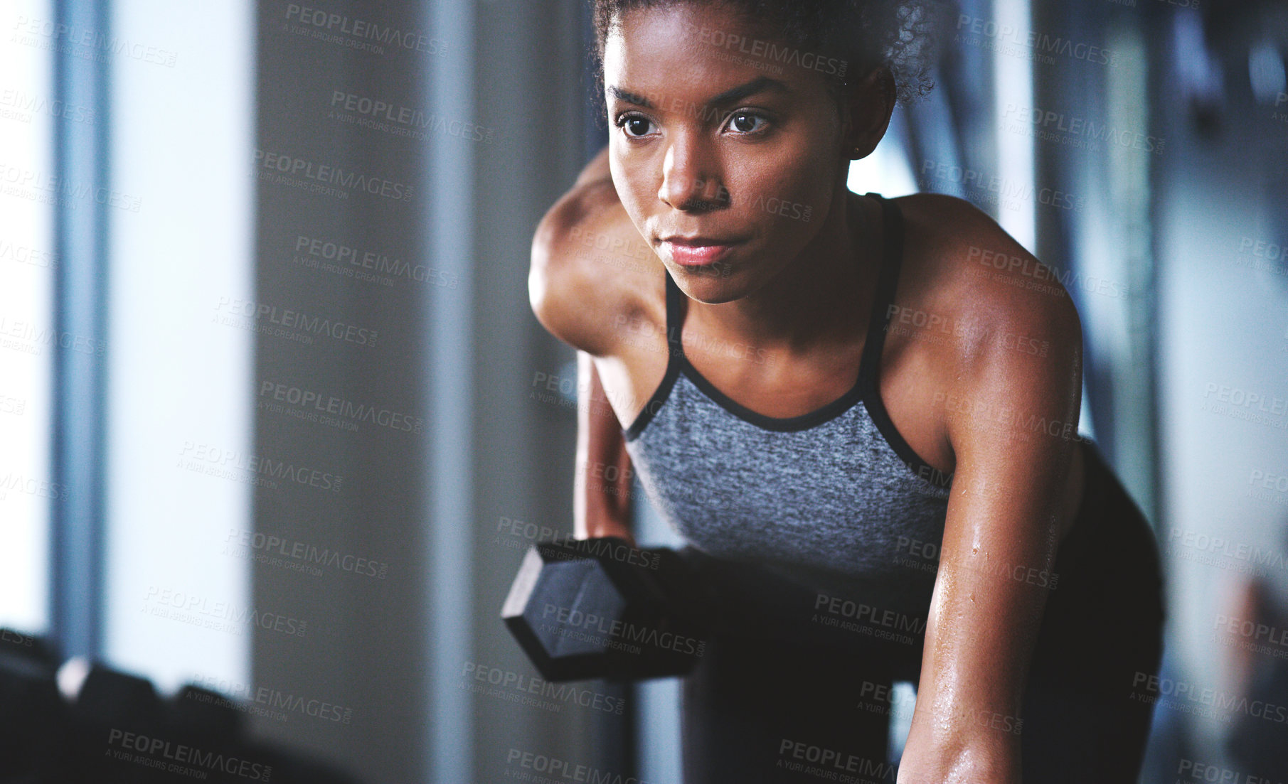 Buy stock photo Shot of a sporty young woman exercising with a dumbbell at the gym