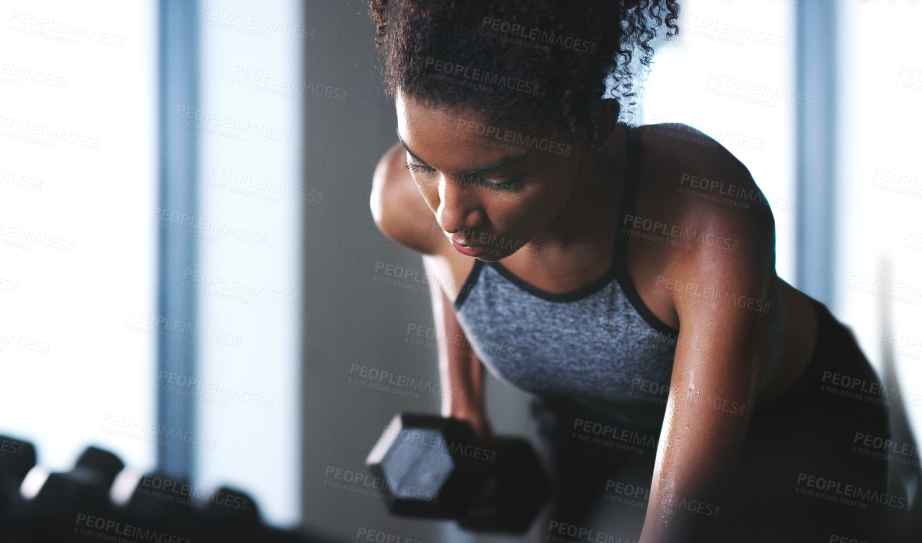 Buy stock photo Shot of a sporty young woman exercising with a dumbbell at the gym