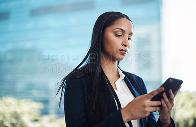 Buy stock photo Shot of a young businesswoman using a smartphone against a city background