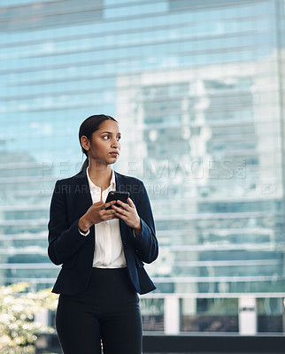 Buy stock photo Shot of a young businesswoman using a smartphone against a city background