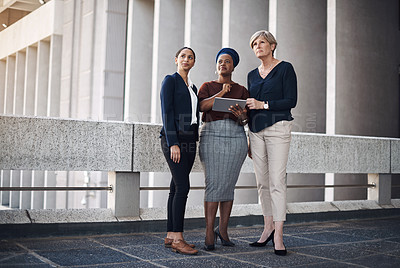 Buy stock photo Shot of a group of businesswomen using a digital tablet together against a city background