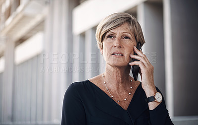 Buy stock photo Shot of a mature businesswoman using a smartphone against a city background