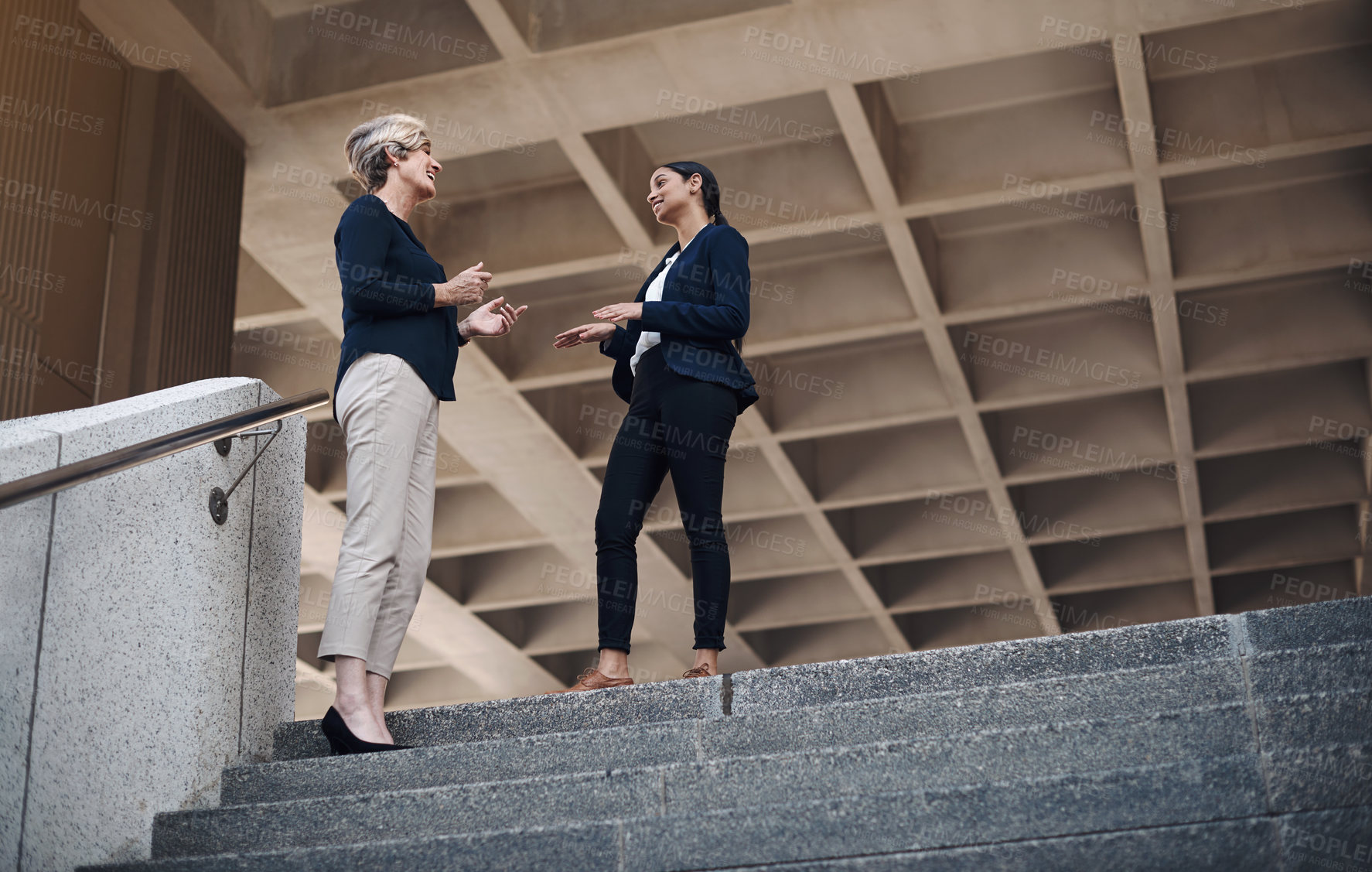 Buy stock photo Shot of two businesswomen having a discussion against a city background