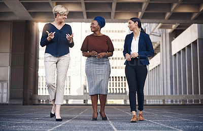 Buy stock photo Walking, discussion and business women in city for travel, morning commute or project feedback. Professional, diversity and employees for partnership, collaboration or conversation in urban town