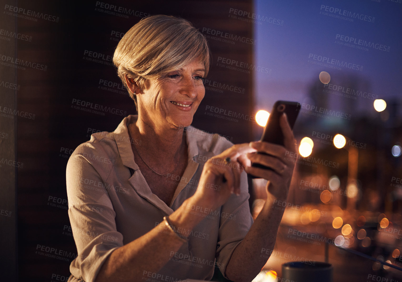 Buy stock photo Cropped shot of an attractive mature businesswoman sending a text while working late in her office