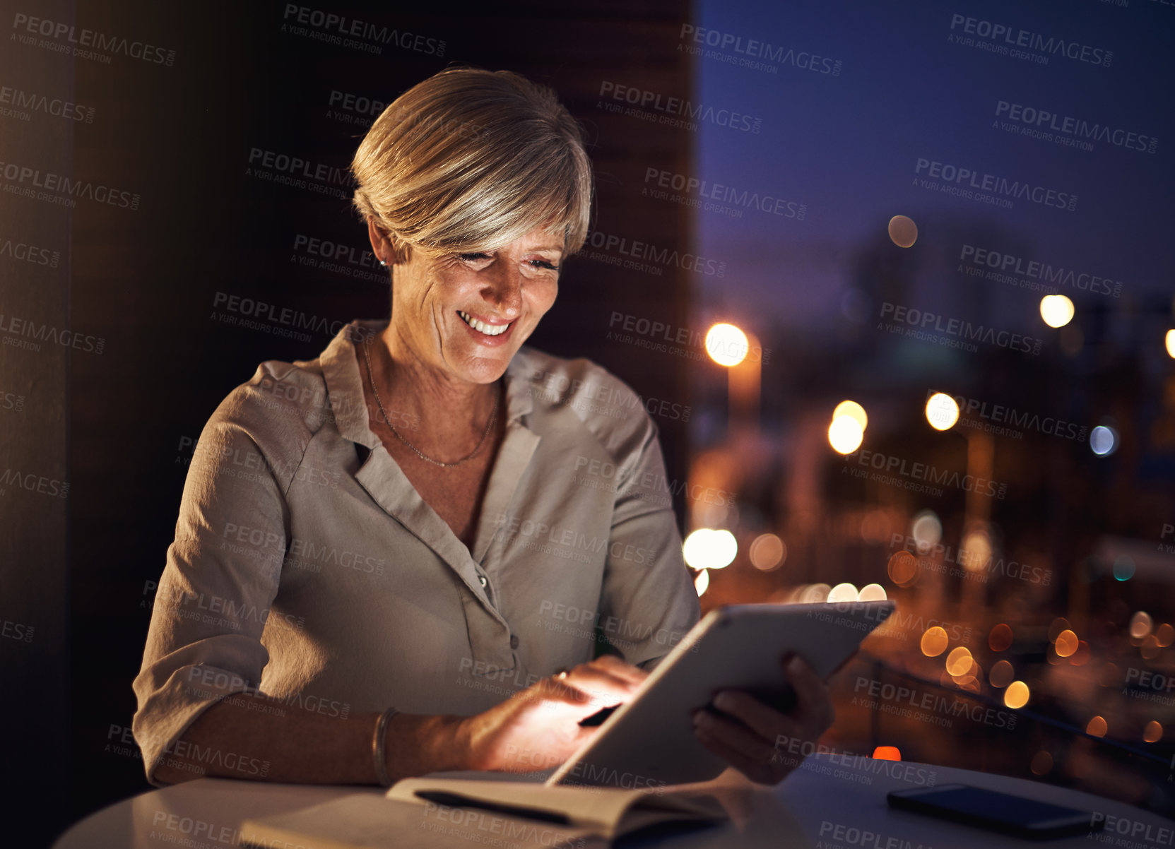 Buy stock photo Cropped shot of an attractive mature businesswoman using her tablet while working late in the office