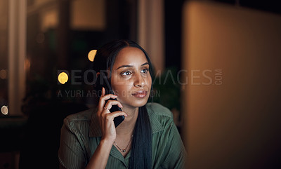Buy stock photo Shot of a young businesswoman talking on a cellphone while using a computer in an office at night