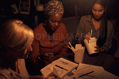 Buy stock photo Shot of a group of businesswomen eating takeout while working together in an office at night