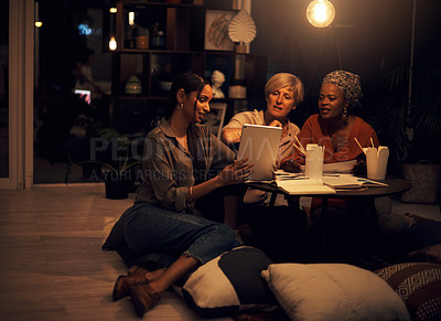 Buy stock photo Shot of a group of businesswomen working together on a digital tablet in an office at night