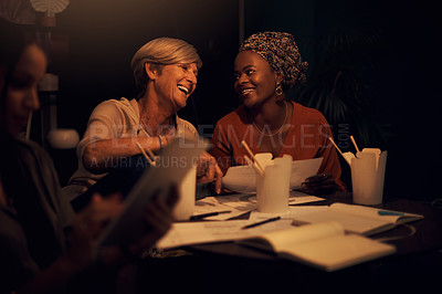 Buy stock photo Shot of two businesswomen going through paperwork together in an office at night