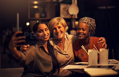 Buy stock photo Shot of a group of businesswomen taking selfies together in an office at night