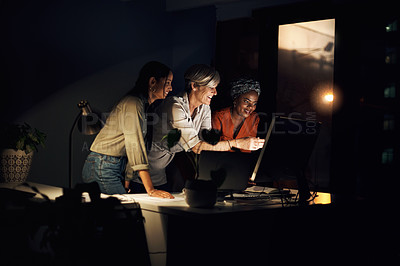 Buy stock photo Shot of a group of businesswomen working together on a computer in an office at night