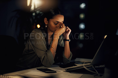 Buy stock photo Shot of a young businesswoman looking stressed out while working in an office at night