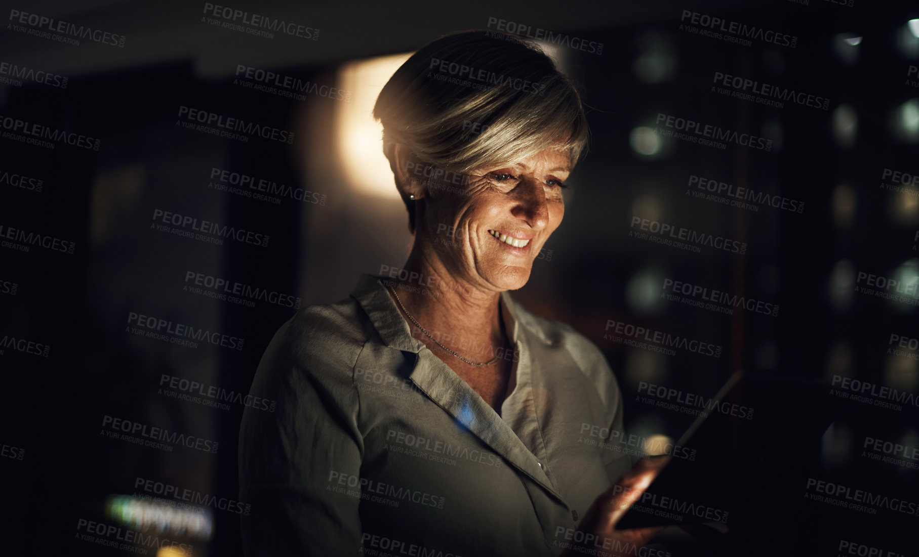 Buy stock photo Shot of a mature businesswoman using a digital tablet in an office at night
