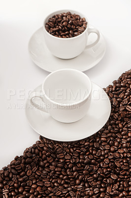 Buy stock photo Closeup shot of an empty cup and one filled with coffee beans against a half-and-half background