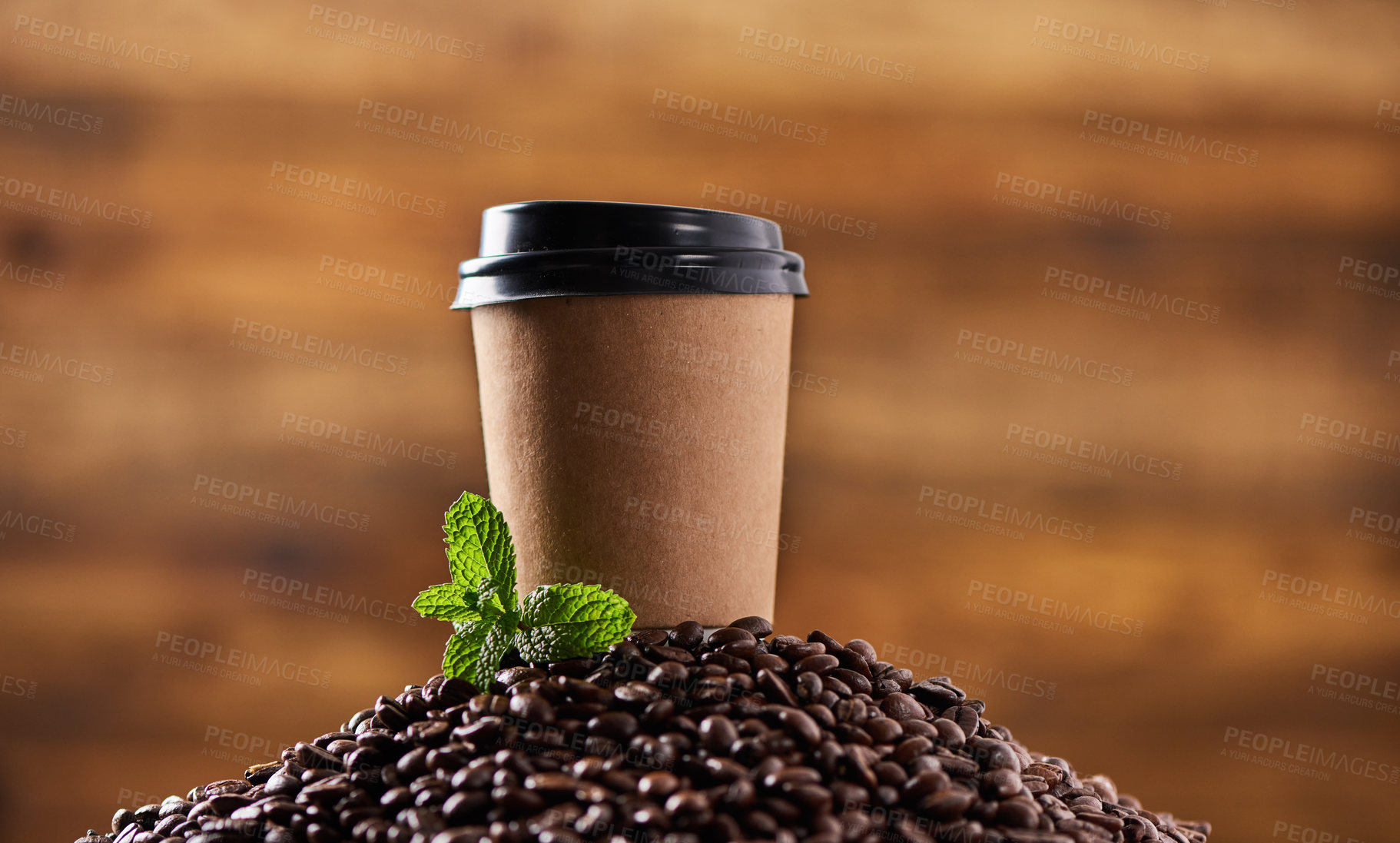 Buy stock photo Closeup shot of a mint leaf and a paper cup on a pile of coffee beans