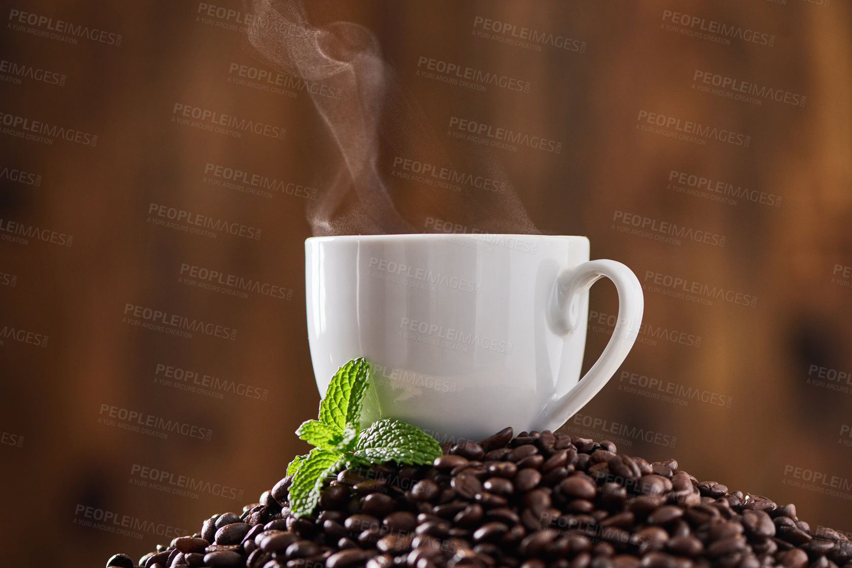 Buy stock photo Closeup shot of a mint leaf and a cup on a pile of coffee beans