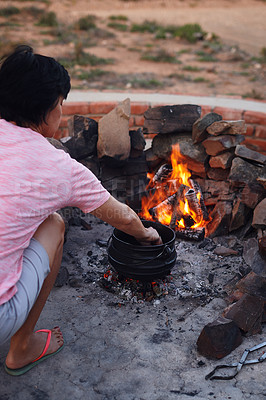 Buy stock photo Shot of a woman cooking traditional South African food by campfire outdoors