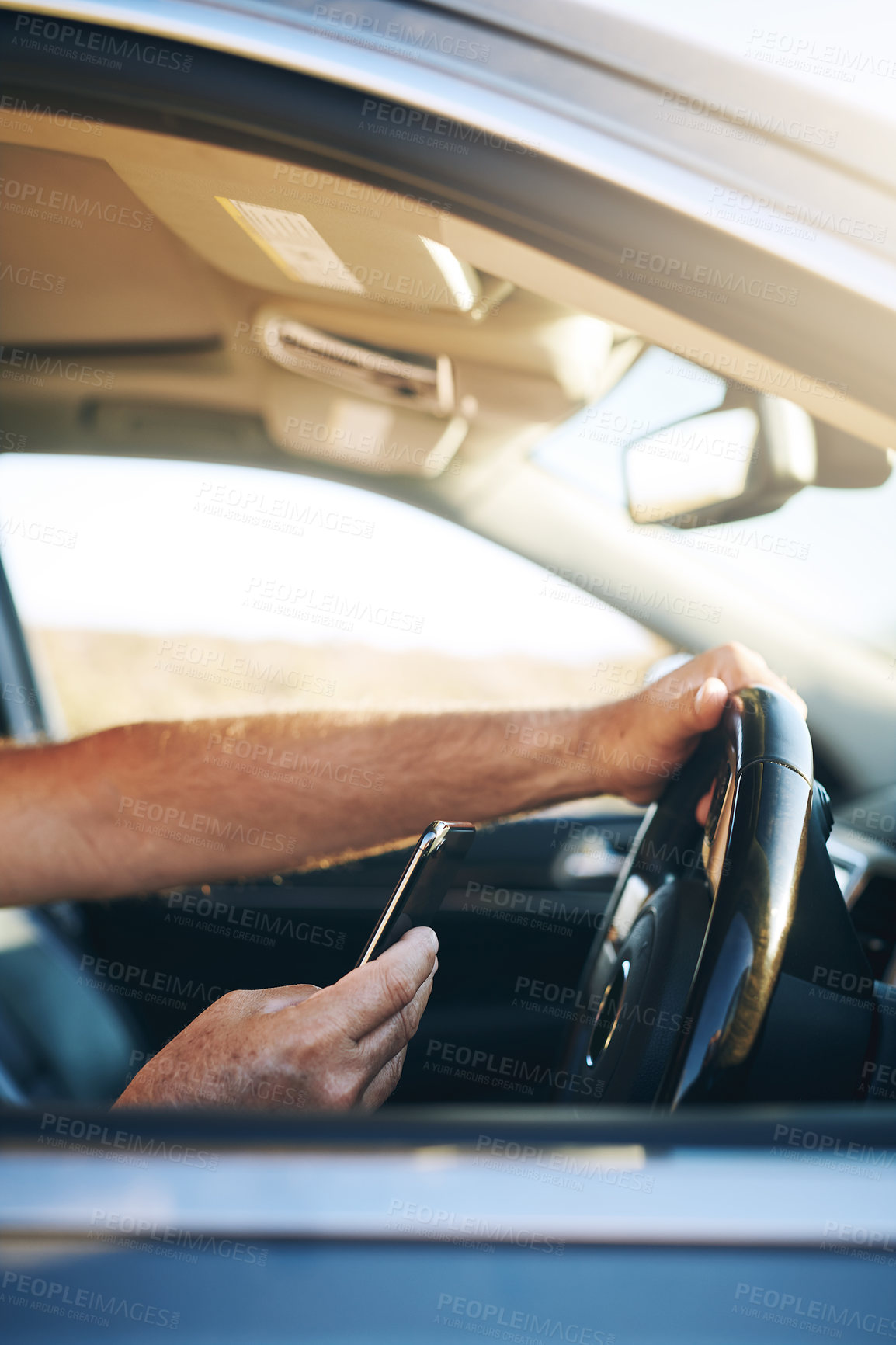 Buy stock photo Shot of an unrecognisable man using a smartphone while driving a car