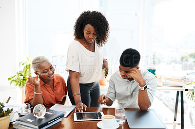 Buy stock photo Shot of a group of businesspeople working together on a digital tablet in an office