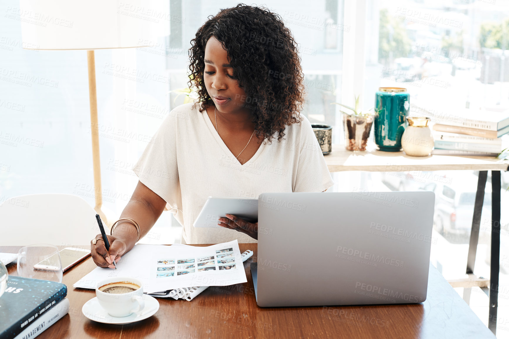 Buy stock photo Shot of a young businesswoman writing notes while working on a digital tablet in an office