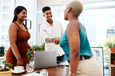 Buy stock photo Shot of a young businessman and businesswoman shaking hands in a modern office