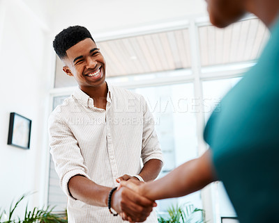 Buy stock photo Shot of a young businessman and businesswoman shaking hands in a modern office