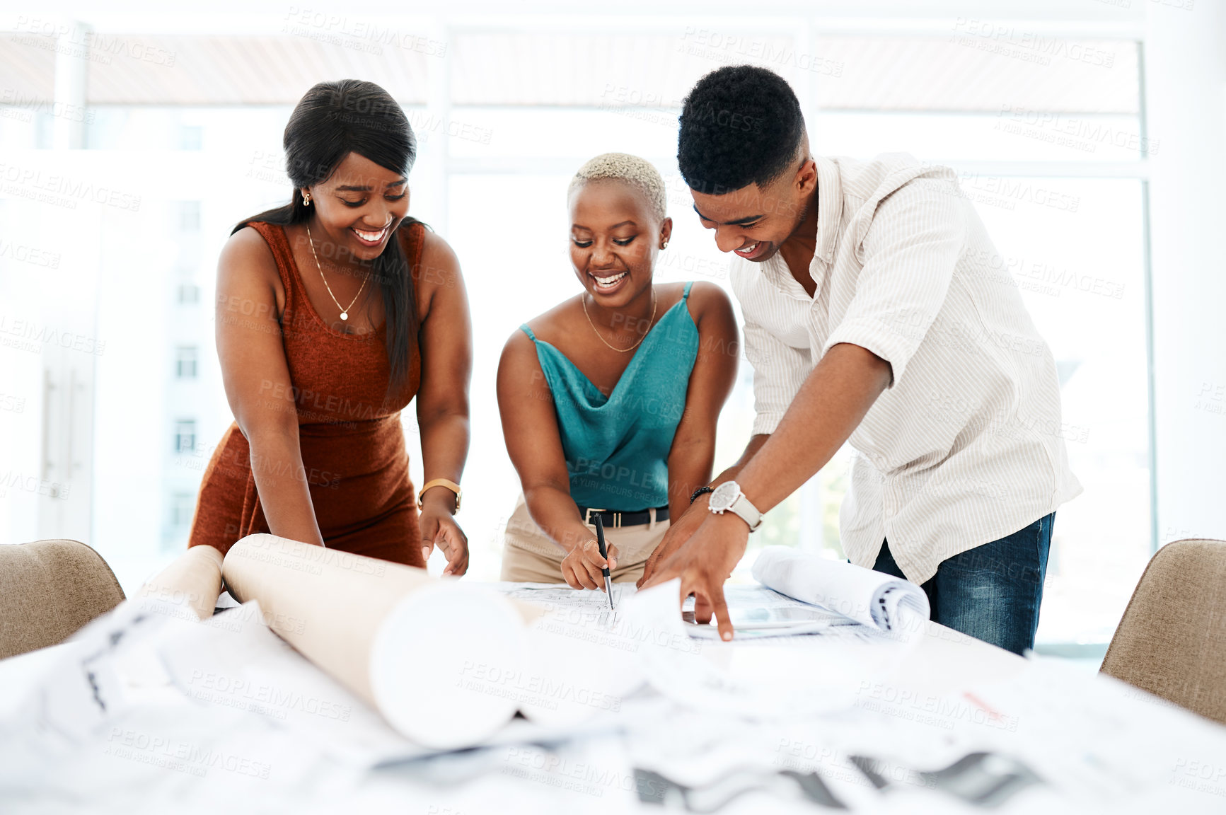 Buy stock photo Shot of a group of young colleagues going over blueprints in a modern office