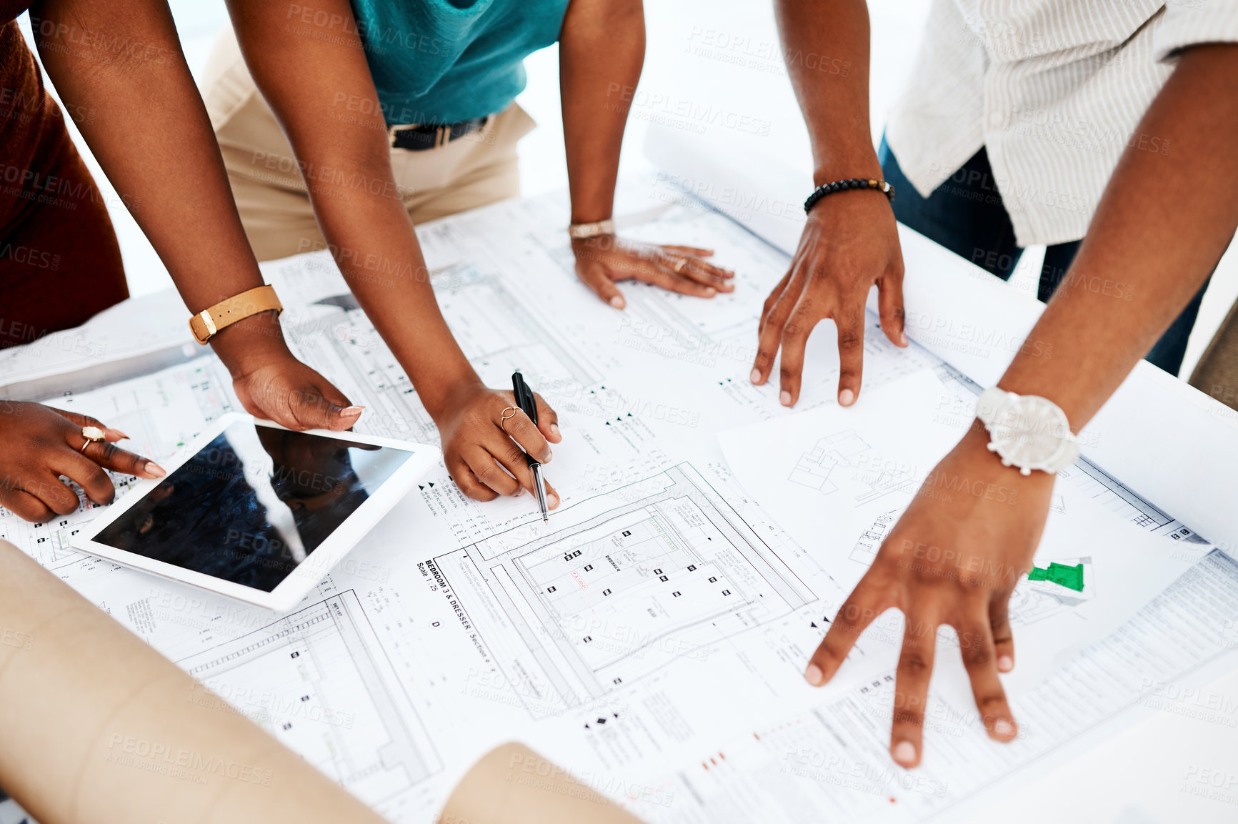 Buy stock photo Cropped shot of a group of colleagues going over blueprints in a modern office