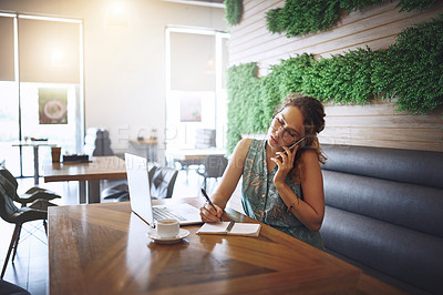 Buy stock photo Shot of a young woman using a laptop and smartphone while working at a cafe