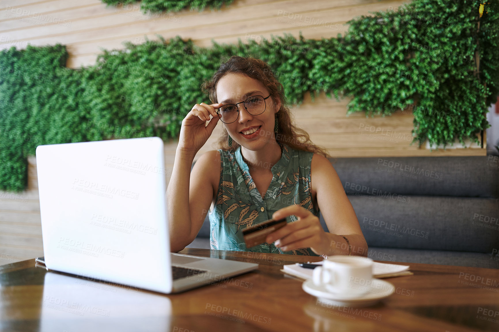 Buy stock photo Shot of a young woman using a laptop and credit card while working at a cafe