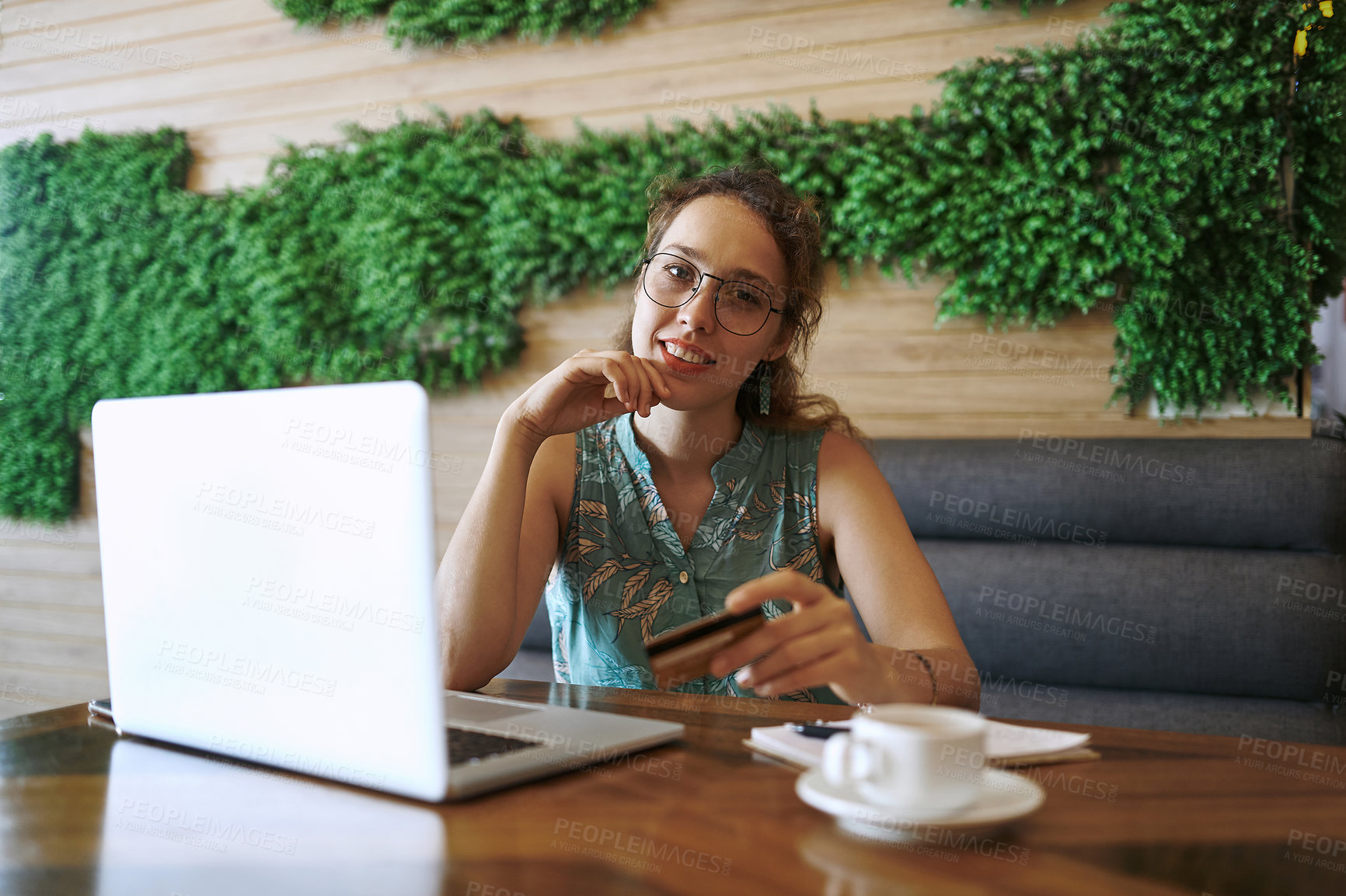 Buy stock photo Shot of a young woman using a laptop and credit card while working at a cafe