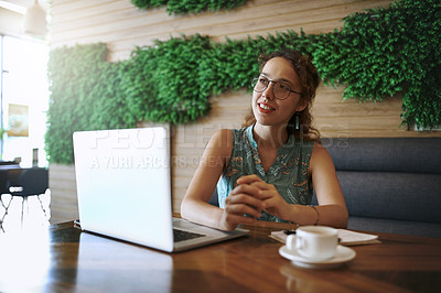 Buy stock photo Shot of a young woman using a laptop while working at a cafe