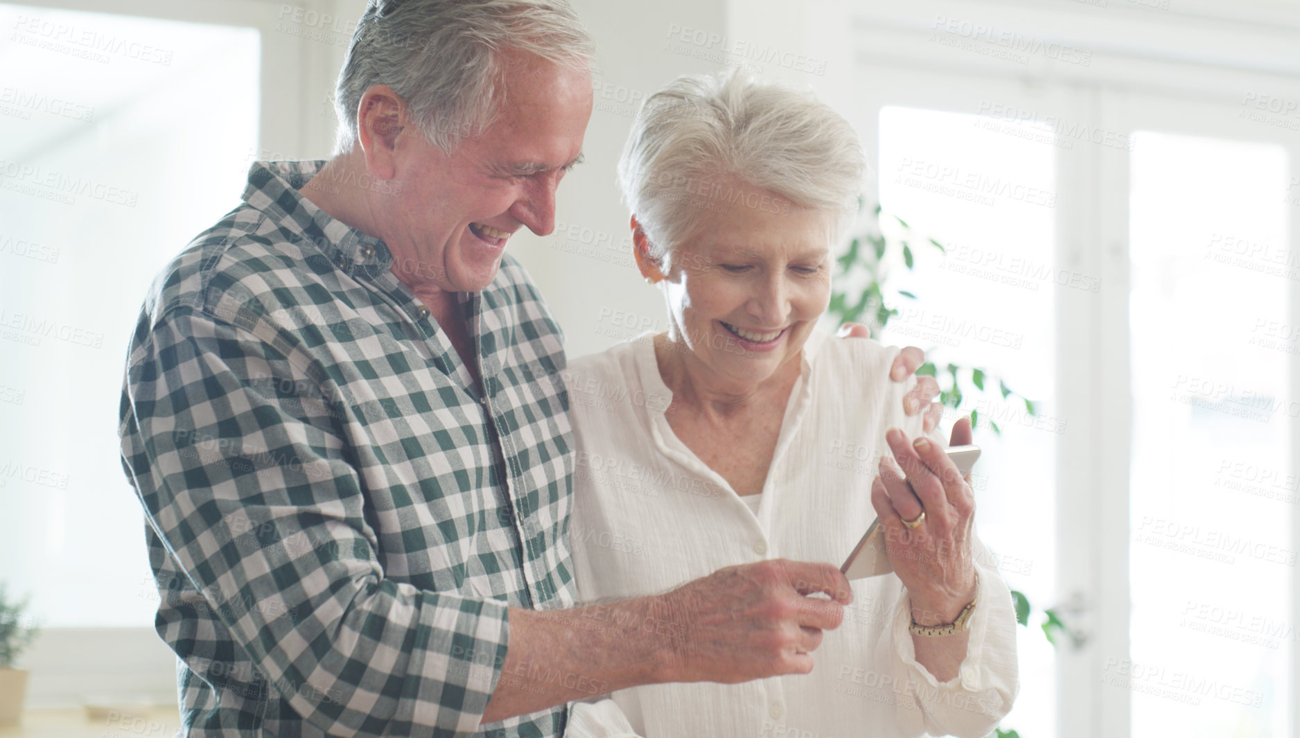 Buy stock photo Cropped shot of a happy senior couple looking at something on a cellphone