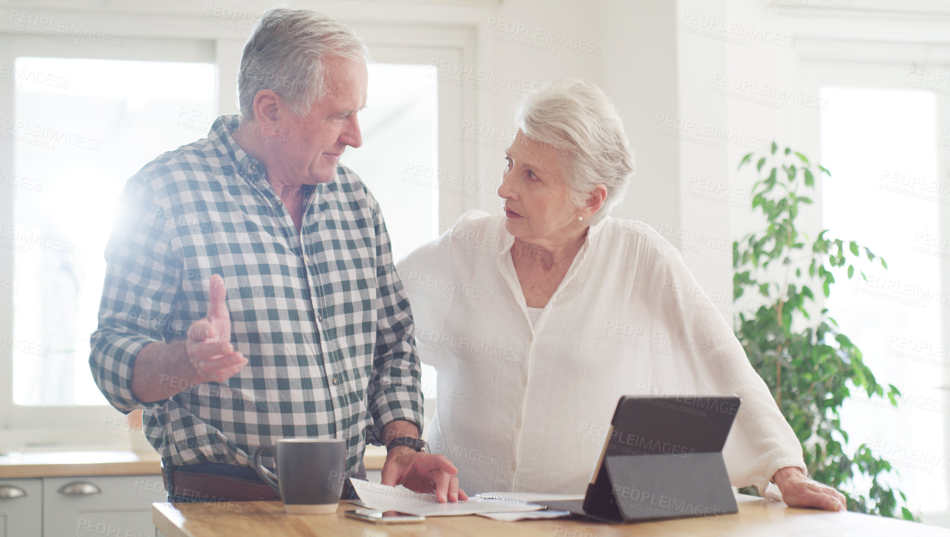 Buy stock photo Cropped shot of a senior couple using a digital tablet while going through paperwork at home