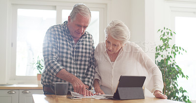 Buy stock photo Cropped shot of a senior couple using a digital tablet while going through paperwork at home